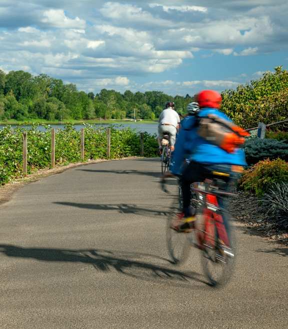 A person riding a bicycle on a paved path next to a body of water.