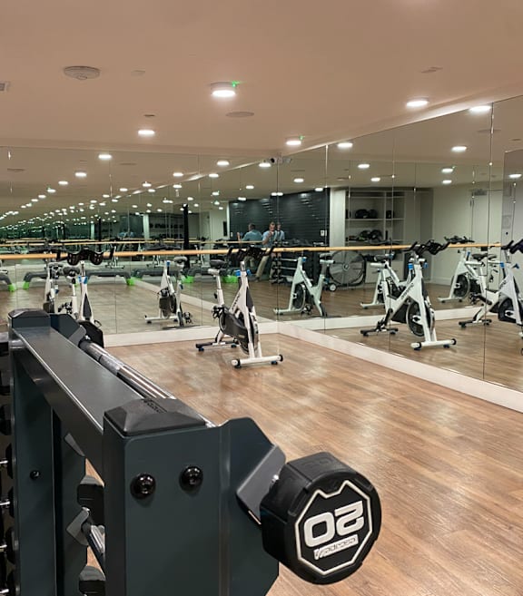 Fusion Hollywood yoga room with wooden floors, weights, and spin bikes