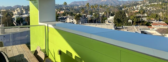 A green building with a view of the city and mountains.