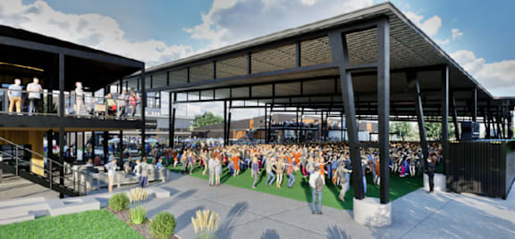 A large group of people are gathered in an outdoor area under a covered walkway.