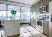 Thumbnail 21 of 33 - Kitchen With Full Set Of Stainless Appliances And Wood-Style Flooring  at The Grand, Kansas City