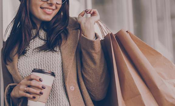 woman holding a cup of coffee and a bunch of shopping bags at Metro Crossing Apartments, Owings Mills, 21117