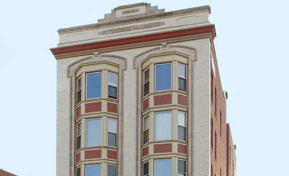 a white building with red trim on the corner of a street