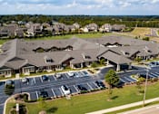 Thumbnail 5 of 11 - A large building complex with a parking lot in front.