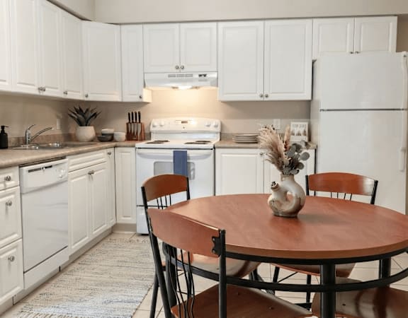 A kitchen with white cabinets and a wooden table.