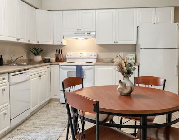 A kitchen with white cabinets and a wooden table.