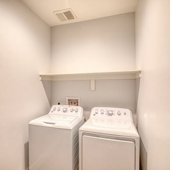 Two white front load washing machines in a small laundry room.