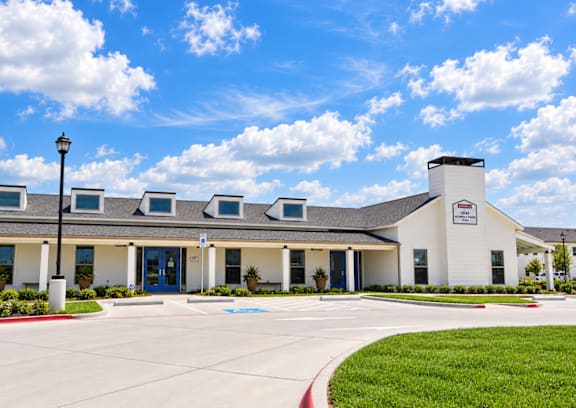 A white building with a sign on it and a blue sky with clouds.