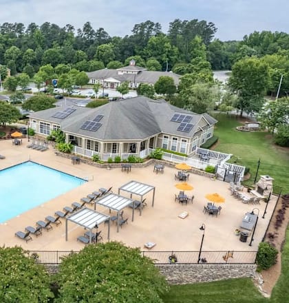 A large swimming pool surrounded by sun loungers and umbrellas in a resort-like setting.
