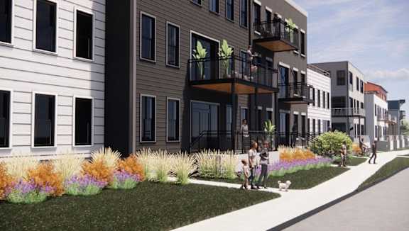 A row of modern townhouses with balconies and flower gardens in front.