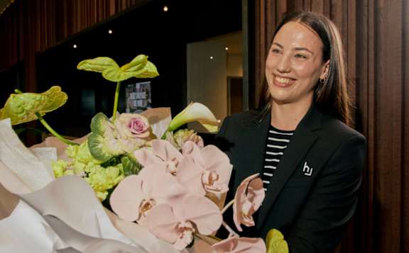 A woman in a black suit walks through a modern lounge area.