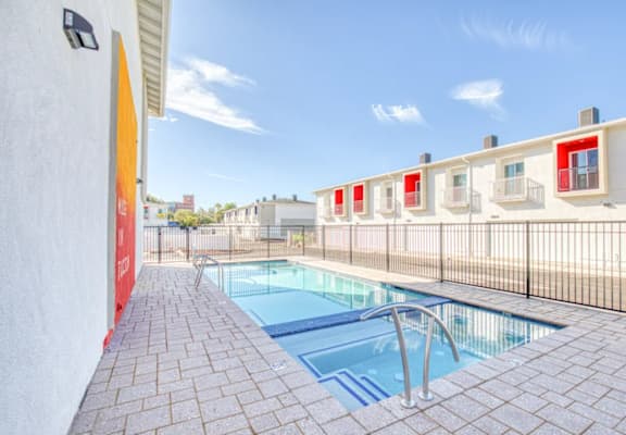 A pool with a metal fence and a red wall.