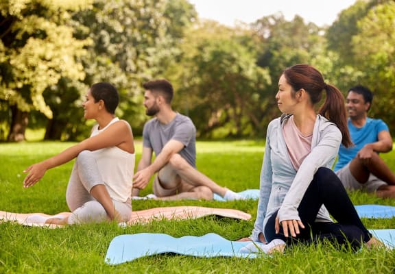 a group of people sitting in a park doing yoga