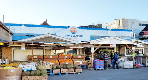 A seafood market with a blue awning and a sign that says "Lam's Seafood".