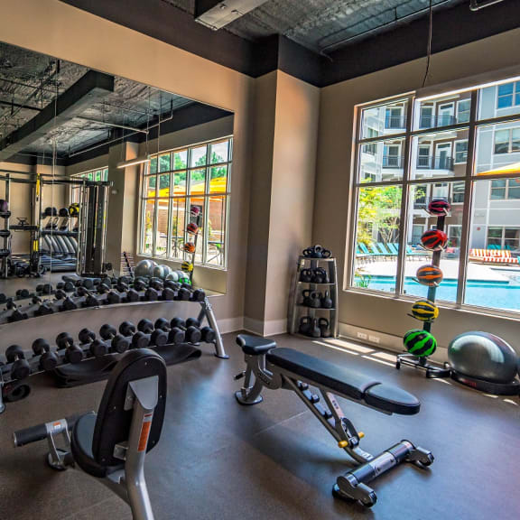 a fitness center with weights and cardio equipment and a large window with a pool in the background  at The Collective NoDa, Charlotte, 28205