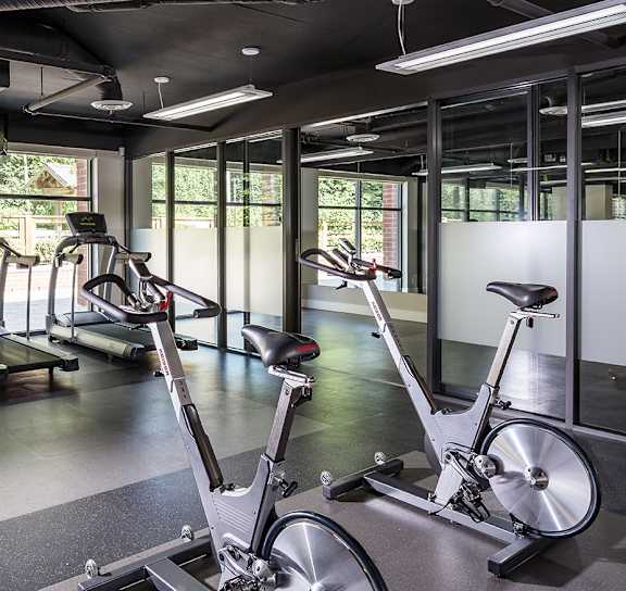 a gym with treadmills and other exercise equipment in a room with a window