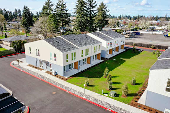 a group of white houses with green grass and trees