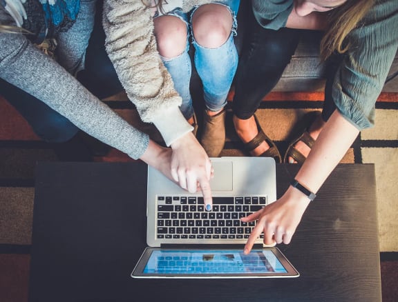 a group of people sitting around a laptop computer