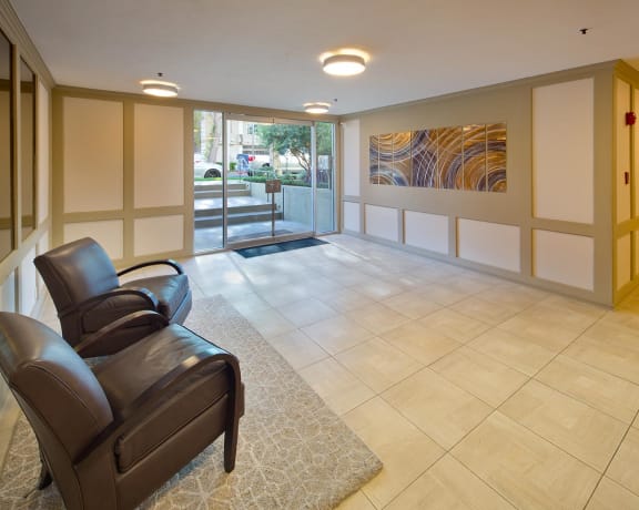 A leather chair sits in a tiled lobby with a painting on the wall.