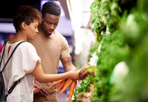 A man and a woman are shopping for vegetables.