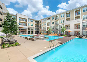 A large swimming pool in front of apartment buildings.