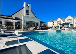 A large swimming pool in front of a building with a white facade.