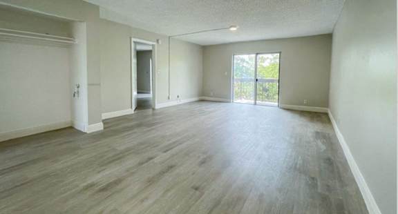 the living room and dining room of an empty house with wood floors