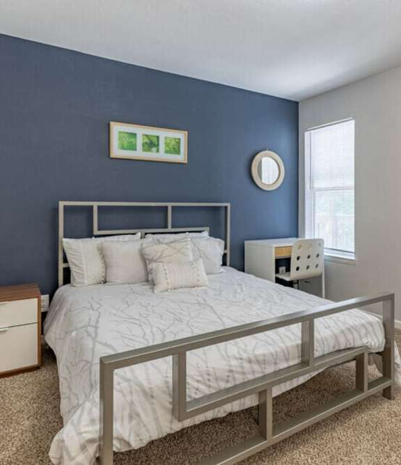 A bedroom with a bed, nightstand, and mirror.