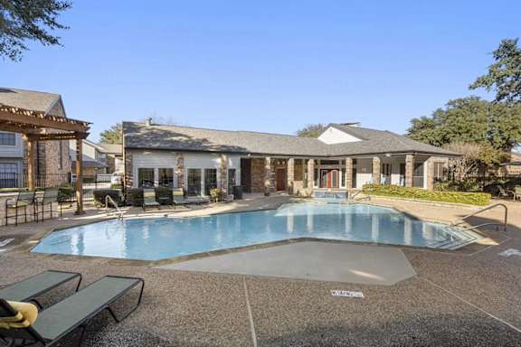 A pool with a bench and a building in the background.