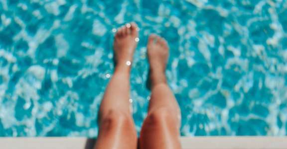a woman with a straw hat laying by a pool