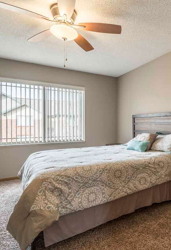 A bedroom with a bed, nightstand, and a ceiling fan.