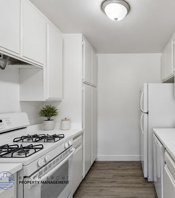 A white kitchen with a stove, sink, and refrigerator.