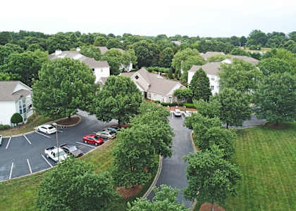 A parking lot with cars and a road leading to a residential area.