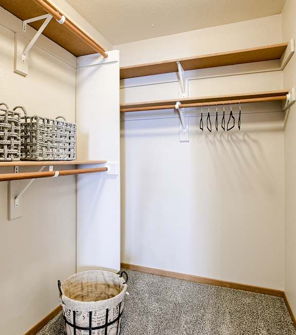 A room with a white wall and a brown shelf.
