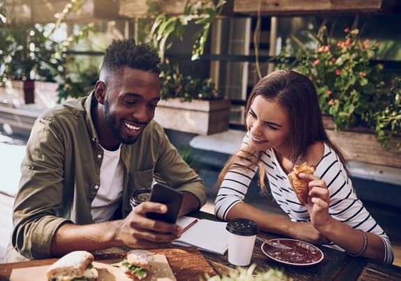 a man and woman sitting at a table looking at a cell phone