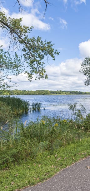 A pathway runs alongside a body of water with greenery on both sides. at Silver Ridge, Minnesota, 55119