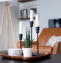 A table with a plate of cheese, a candle holder with three candles, and a potted plant.