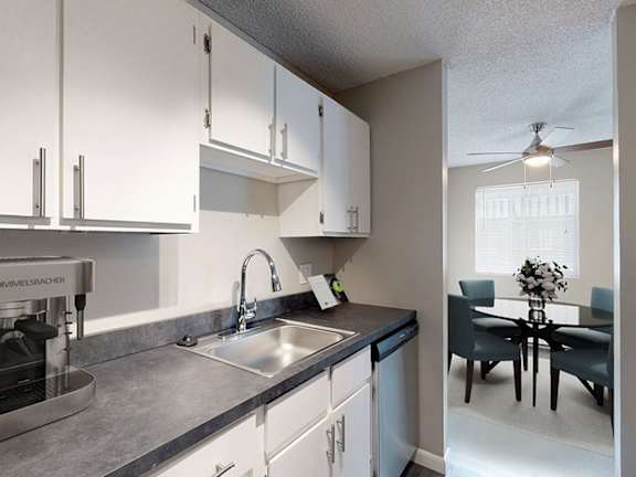 A kitchen with a stainless steel oven and a dining area with a table and chairs.