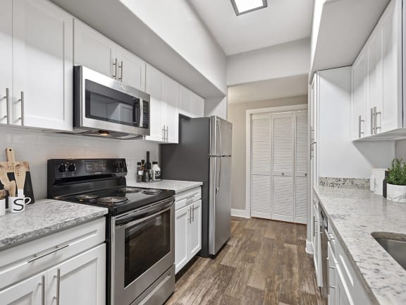 Model Kitchen with White Cabinets and Wood-Style Flooring at Park West Apartments located in Houston, TX-LRGAM.