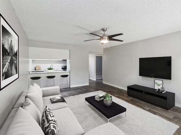 Model Living Room with Wood-Style Flooring and View of Kitchen at Indigo Park Apartments located in Albuquerque, NM-LRGAM.