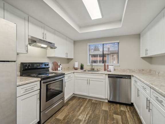 Model Kitchen with White Cabinets and Wood-Style Flooring at Grammercy Apartments located in Renton, WA-LRGAM.