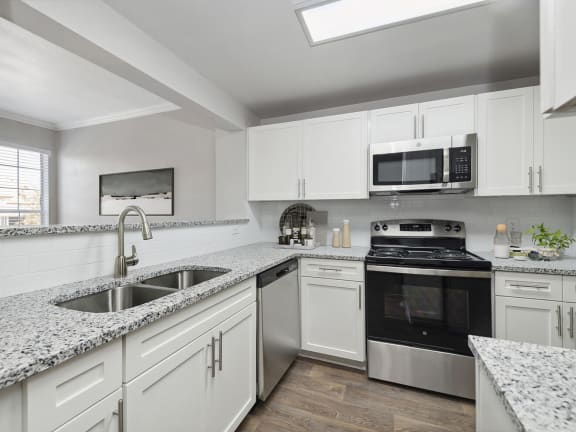 Model Kitchen with White Cabinets and Wood-Style Flooring at Chapel Hill Apartments in Lewisville, TX-LRGAM.