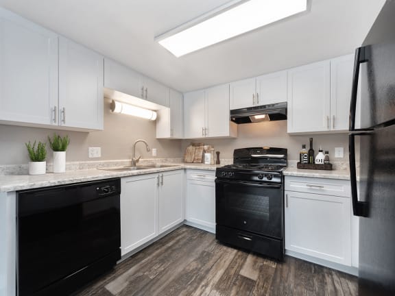 Model Kitchen with White Cabinets and Wood-Style Flooring at Bridges at 9 Mile Station Apartments in Denver, CO-LRGAM.
