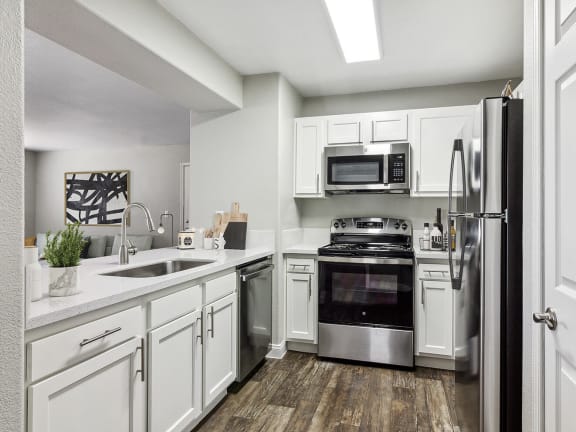 Model Kitchen with White Cabinets and Wood-Style Flooring at Monterra Apartments located in Las Vegas, NV-LRGAM.