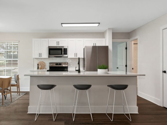 Model Kitchen with White Cabinets, Wood-Style Flooring and Patio Accessibility at Park at Caterina Apartments located in Charlotte, NC-LRGAM.