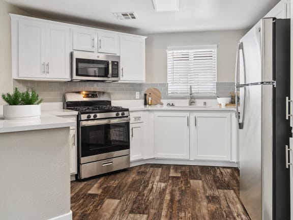 Model Kitchen with White Cabinets and Wood-Style Flooring at Reserve at Rancho Apartments located in Moreno Valley, CA-LRGAM.