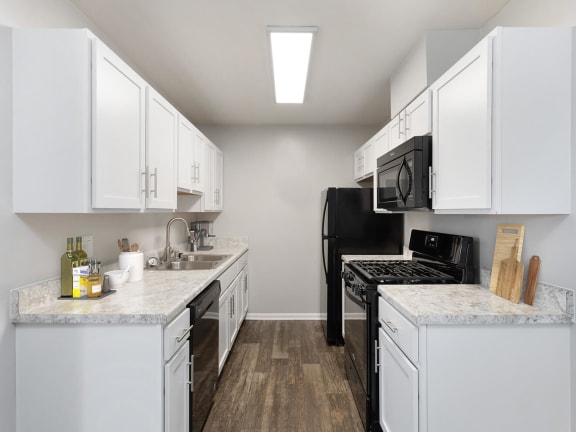 Model Kitchen with White Cabinets and Wood-Style Flooring at Brightwood Forest Apartments in Dale City, VA-LRGAM.