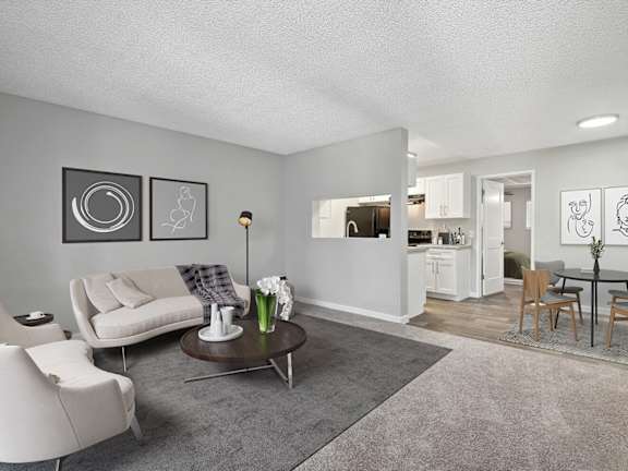 Model Living Room with Carpet and View of Kitchen at Stillwater Apartments located in Glendale, AZ-LRGAM.
