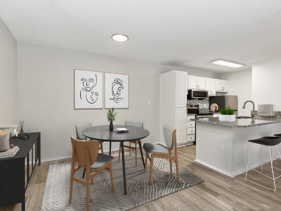 Model Dining Room with Wood-Style Flooring and View of Kitchen at Seven Lakes at Carrollwood Apartments in Tampa, FL.