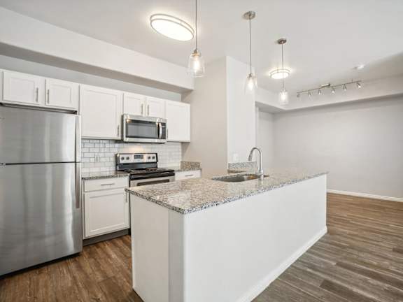 Model Kitchen with Wood-Style Flooring, White Cabinets, and Stainless-Steel Appliances at Altitude on Fifth Apartments located in Salt Lake City, UT.